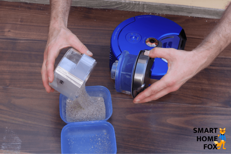 Emptying the mobile dust bin of a robotic vacuum cleaner by hand.